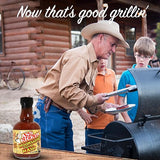 Ass Kickin' Moonshine Pepper Mash on a table. Cowboy grilling sausages on a smoker in the background.